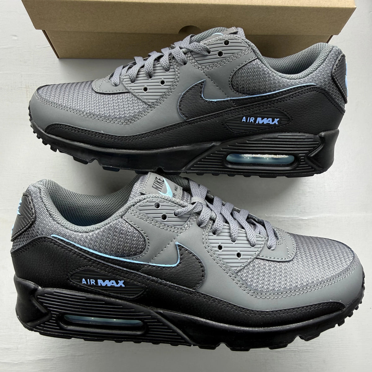 Nike Air Max 90 grey trainers with blue accents and logo detail.