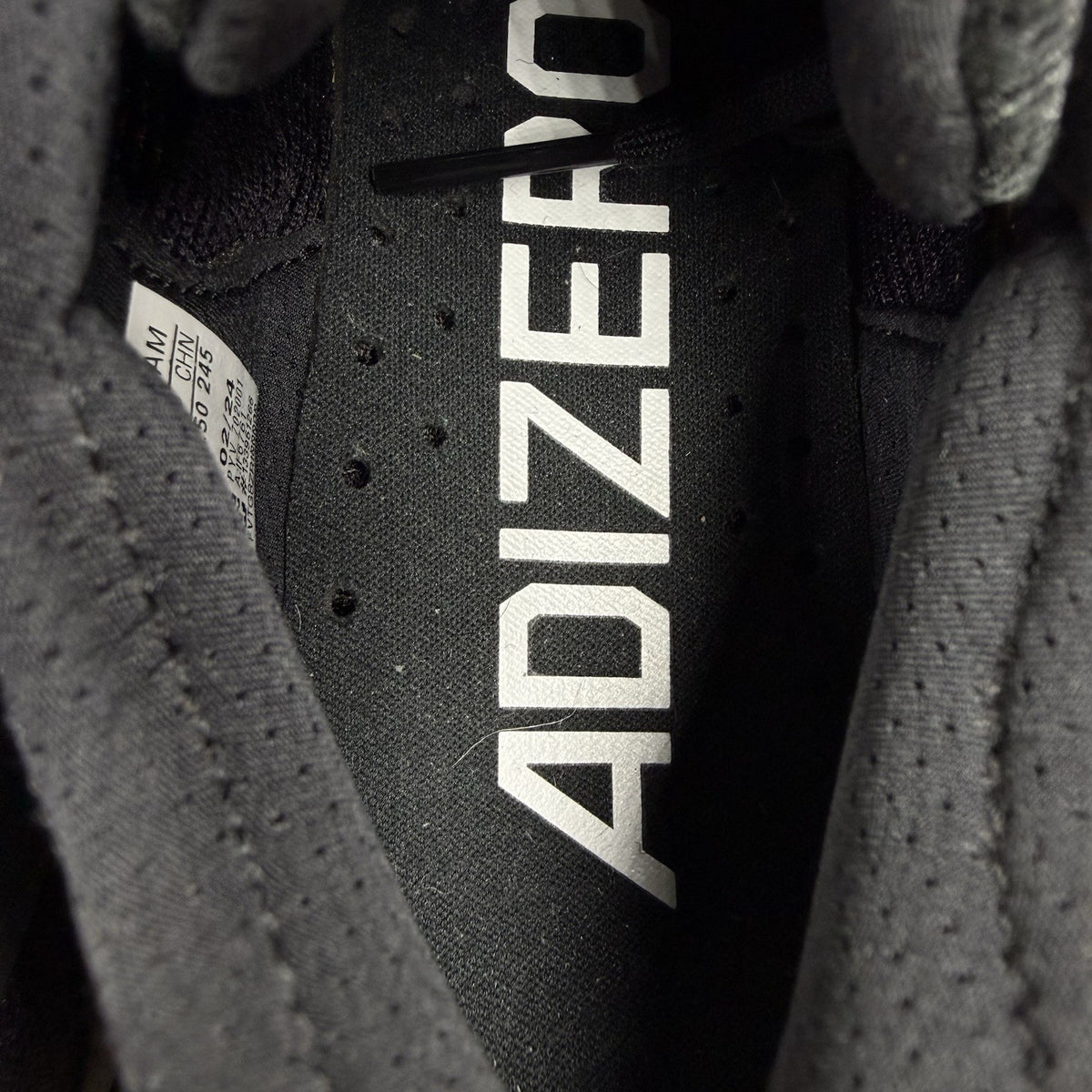 Adidas black trainers with white accents and distinctive Adizero branding.