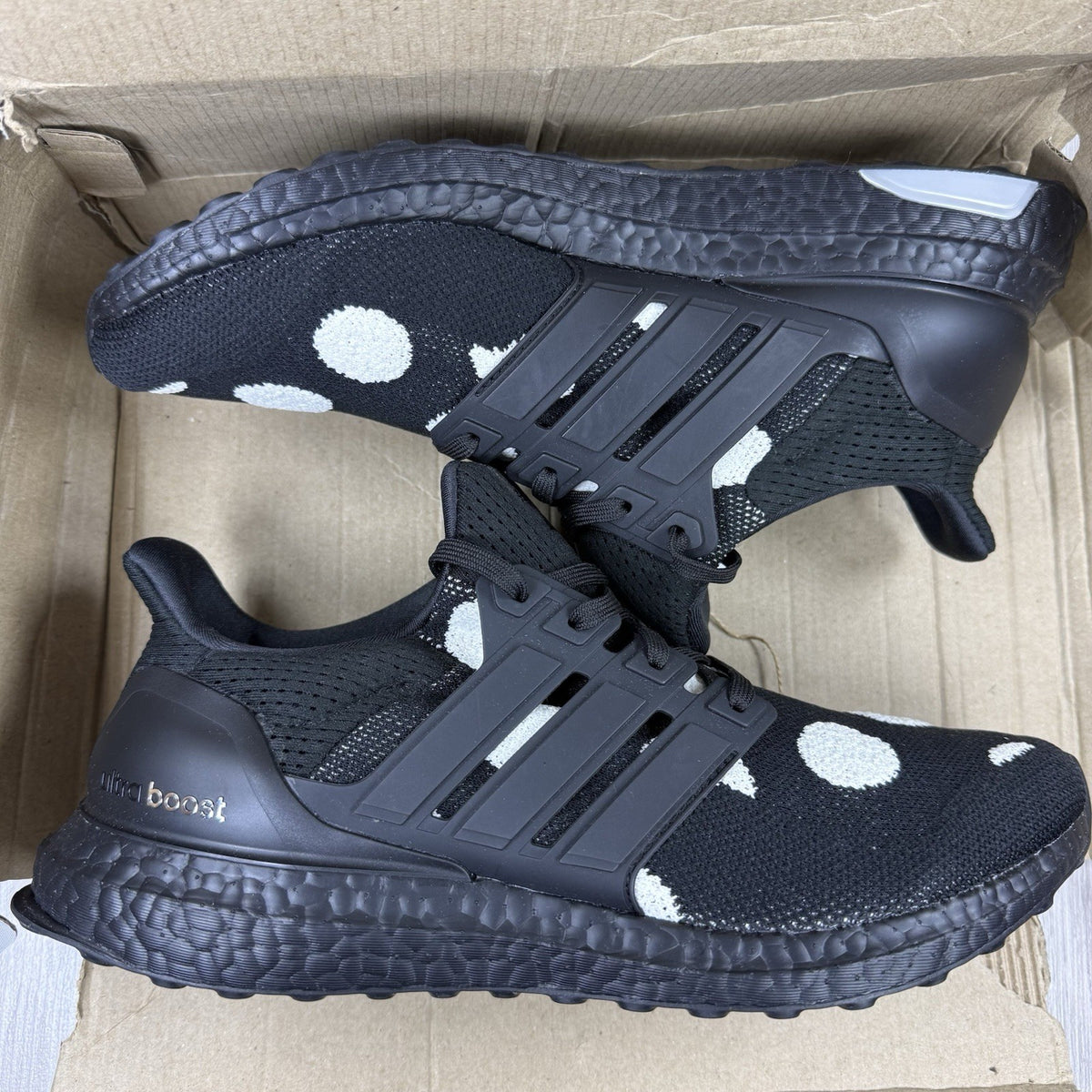 Adidas black trainers with white polka dot pattern and iconic three-stripe logo.