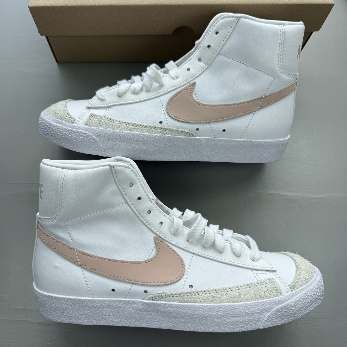 Nike Blazer Mid 77 white trainers with pink accents and retro logo design.