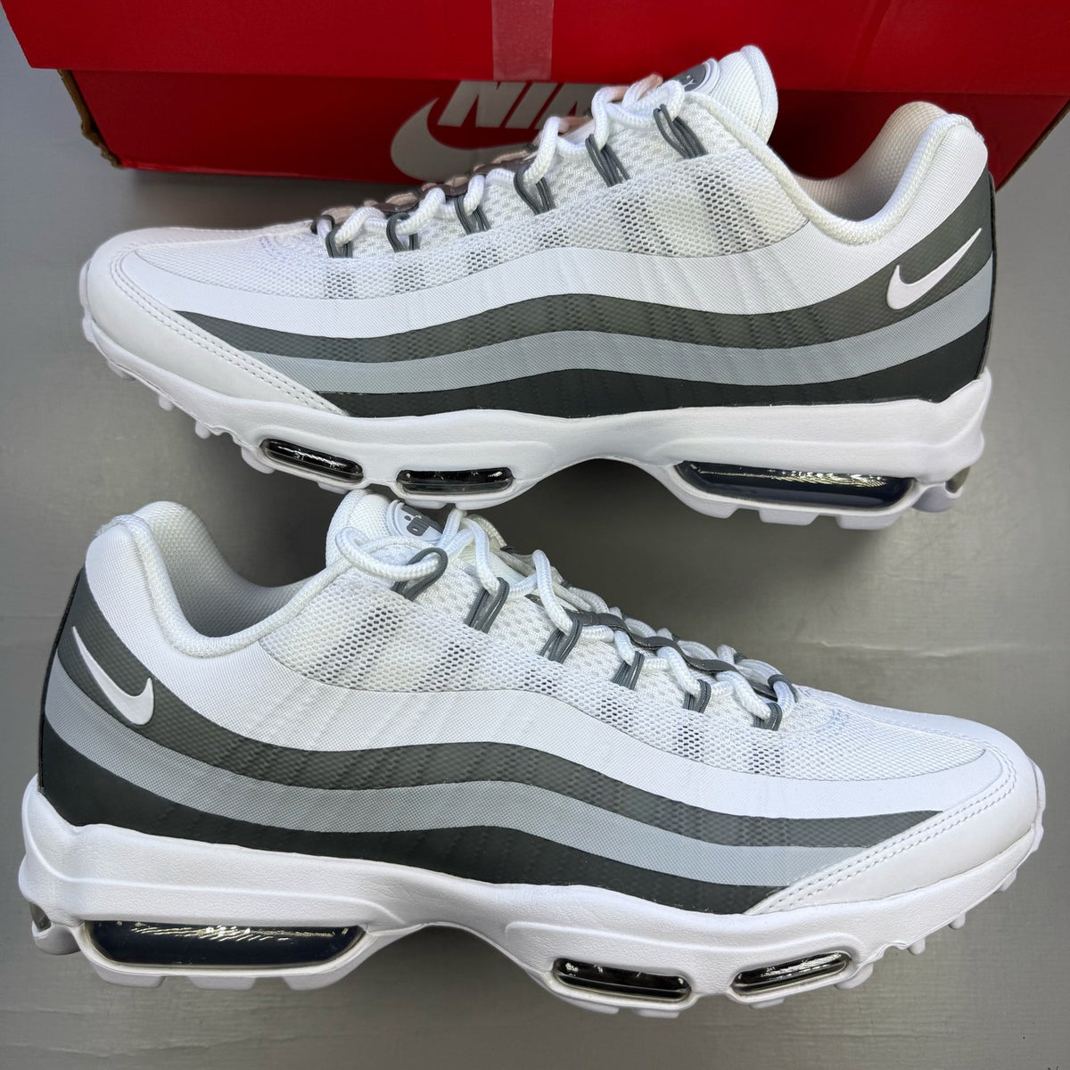 Nike Air Max 95 white trainers with grey accents and signature swoosh logo.