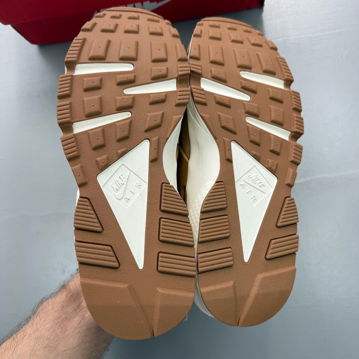 Nike brown trainers with gum sole and white accents, featuring iconic Huarache design.