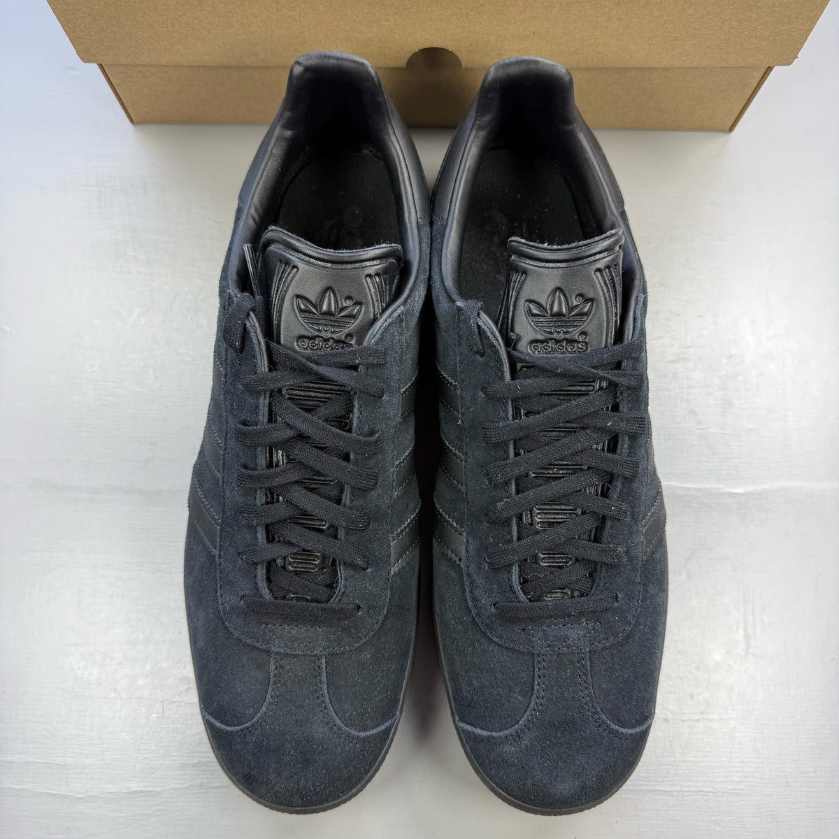 Adidas black trainers in suede with iconic three stripes logo and classic design.
