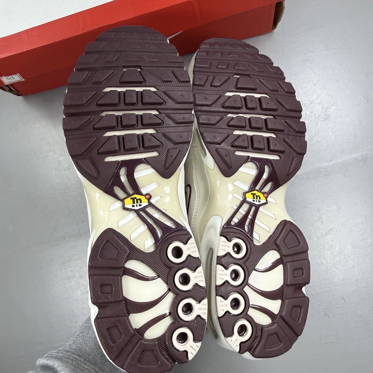 Nike Air Max Plus trainers white with burgundy accents and signature logo details.