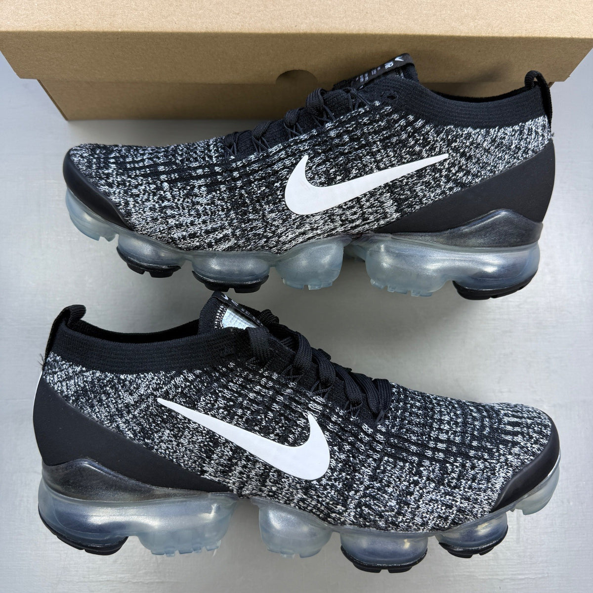 Nike athletic shoes black Flyknit design with white accents and VaporMax sole.