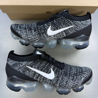 Nike athletic shoes black Flyknit design with white accents and VaporMax sole.
