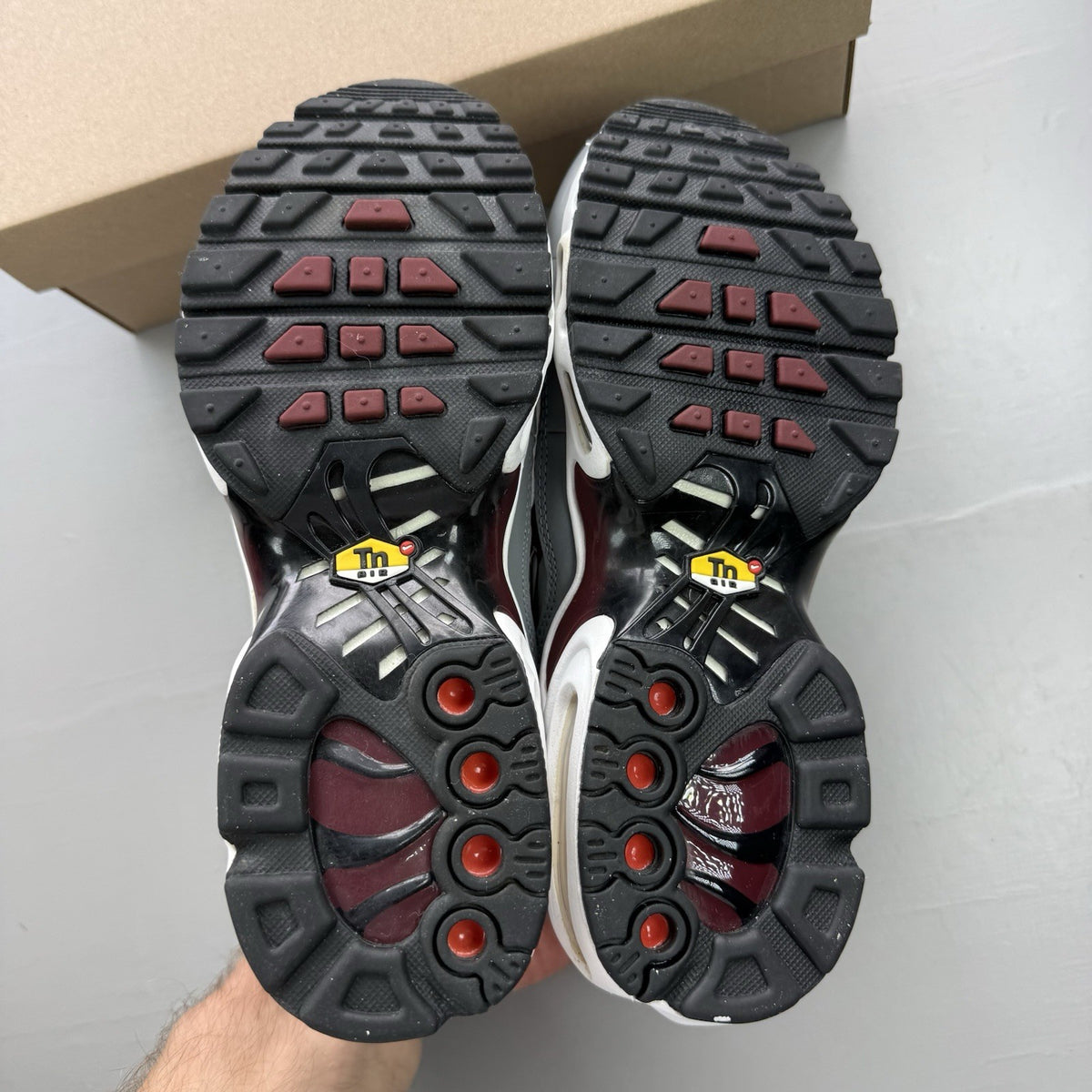 Nike Air Max Plus TN white trainers with red and black accents, featuring logo detailing.
