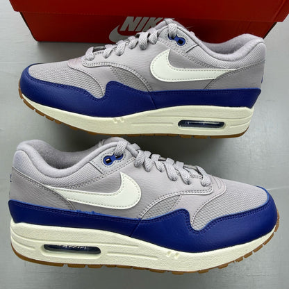 Nike Air Max 1 grey trainers with royal blue accents and signature logo.