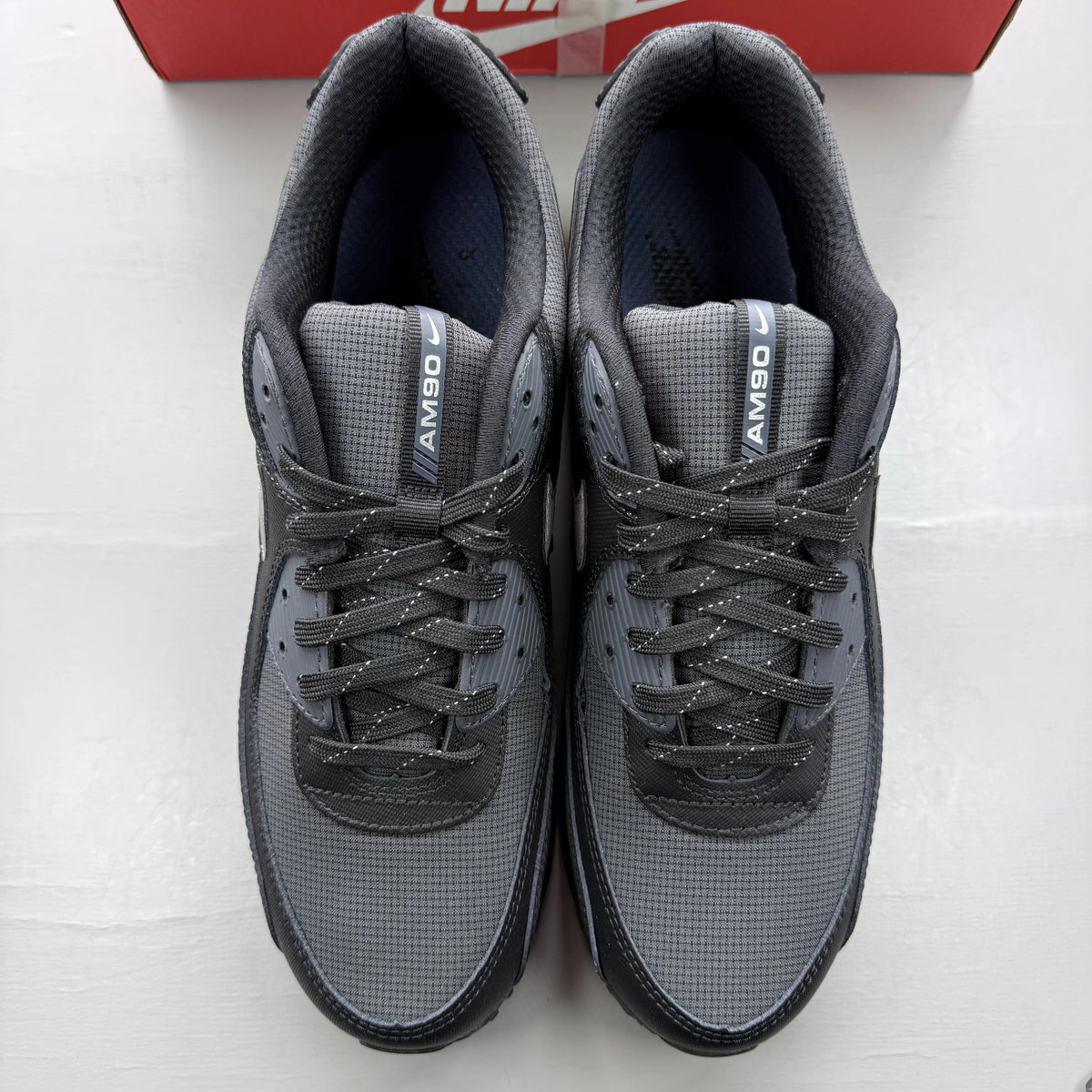 Nike Air Max 90 black sneaker with reflective silver accents and logo details.