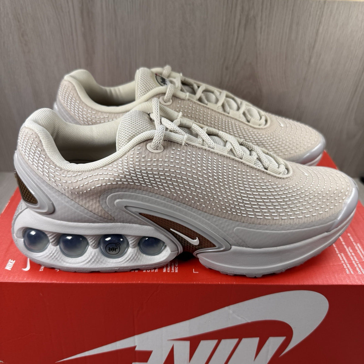 Nike Air Max DN trainers white with light brown accents and logo detail.