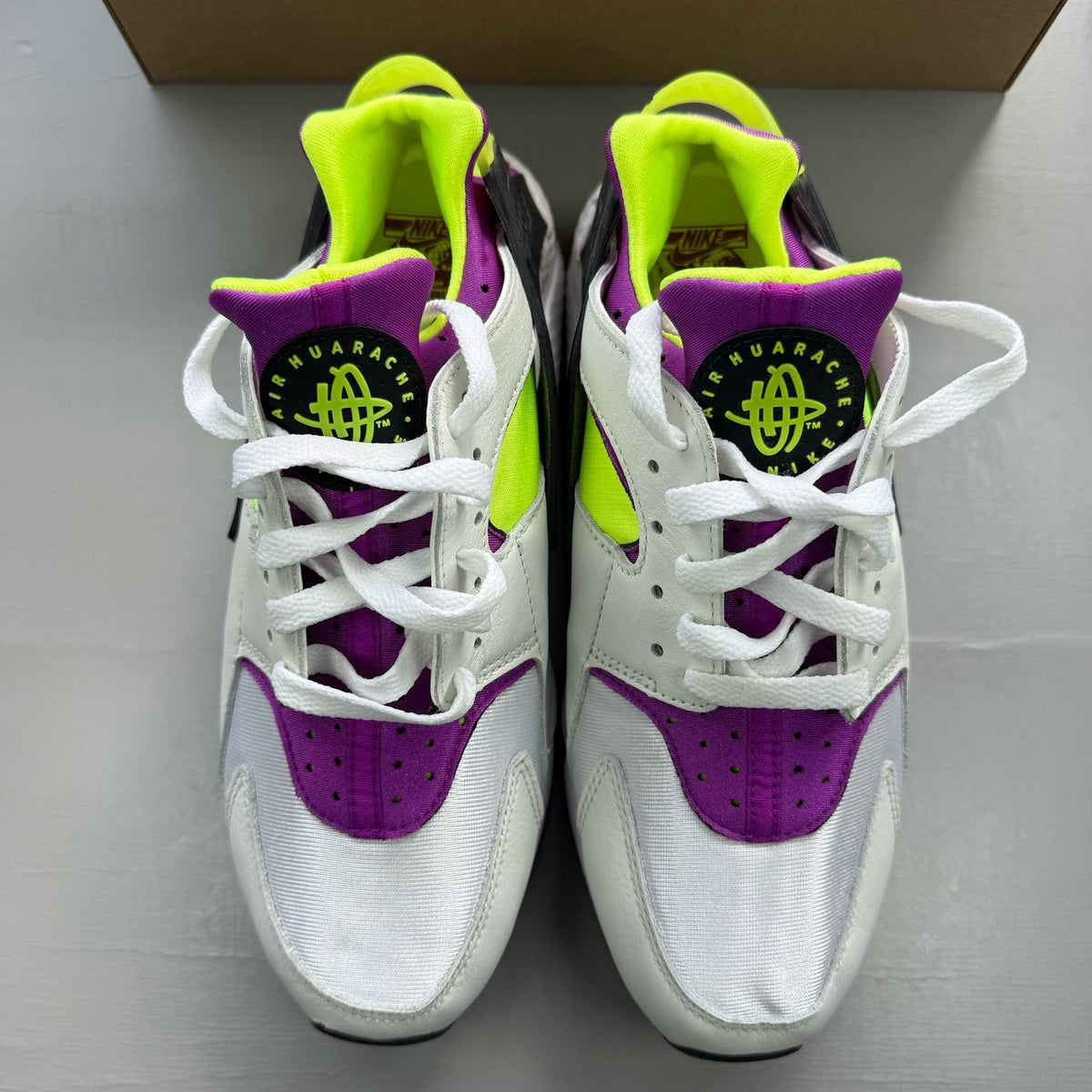 Nike white trainers with magenta and neon yellow accents, featuring classic Huarache design.