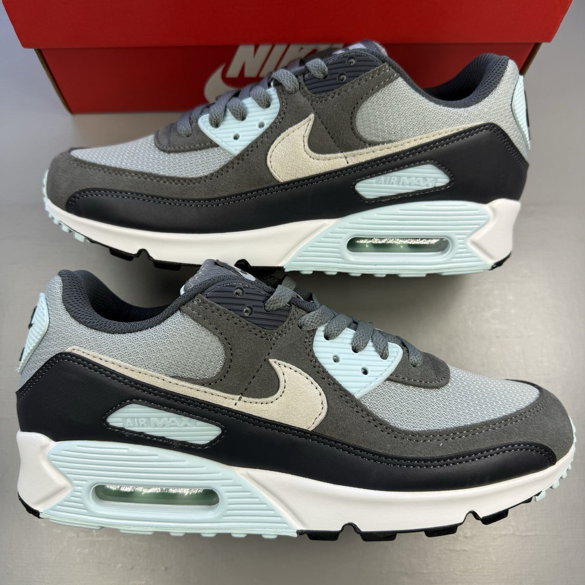 Nike Air Max 90 grey trainers with blue and white accents, featuring iconic logo.
