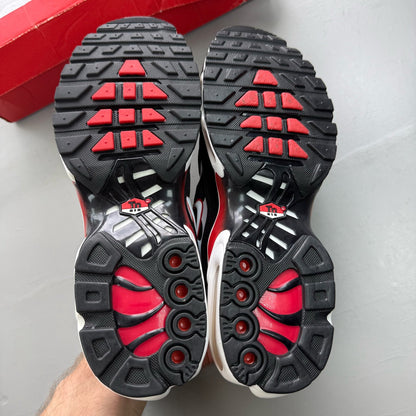 Nike Air Max Plus TN black trainers with white and university red accents, mesh material.