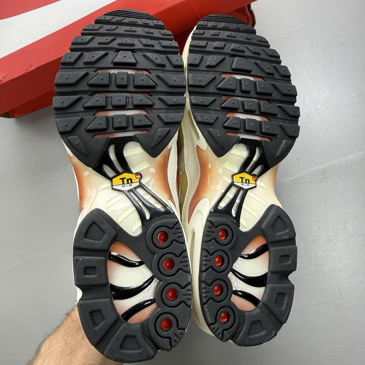 Nike Air Max Plus TN white trainers with peach accents and signature swoosh logo.