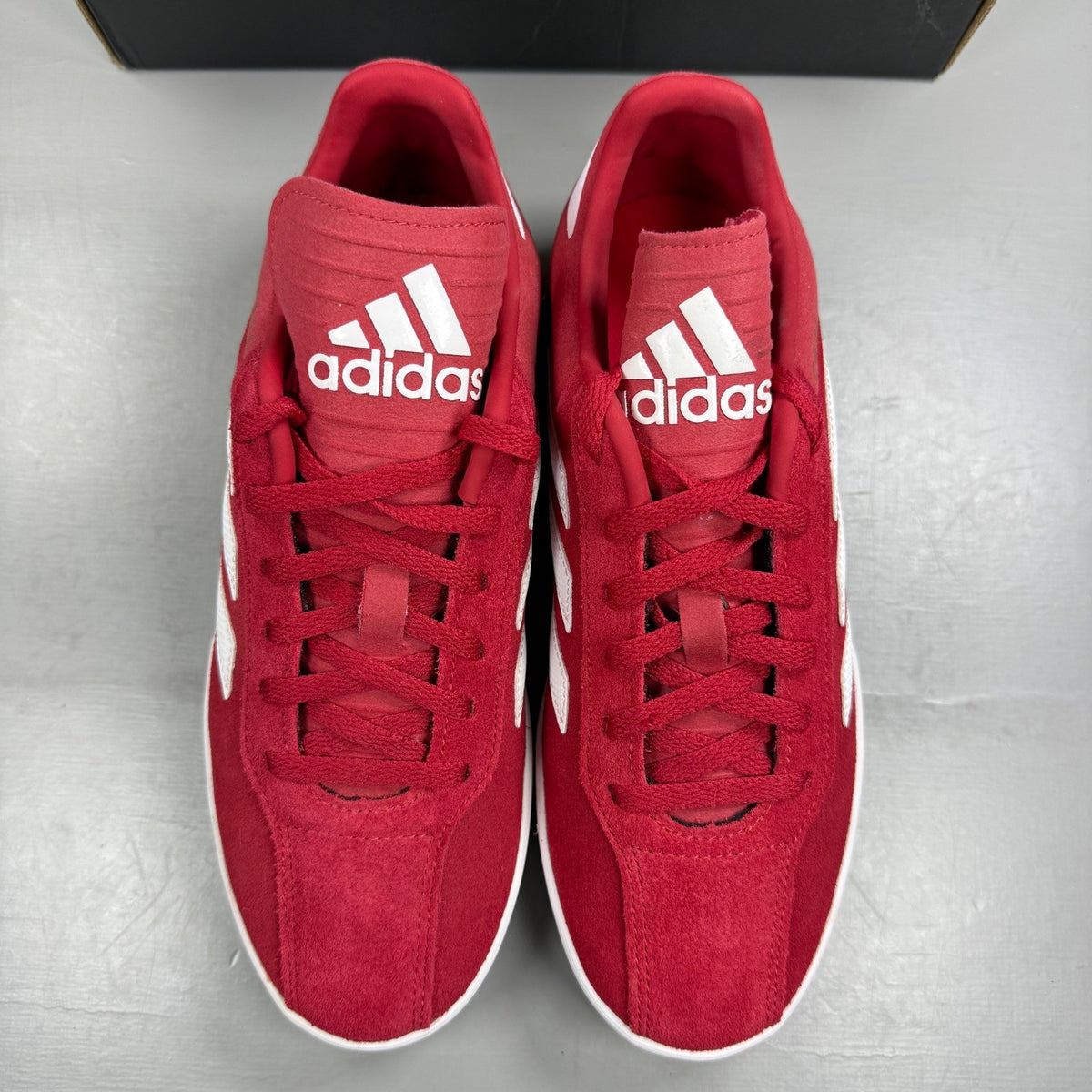 Adidas red suede running trainers with white logo and classic design details.