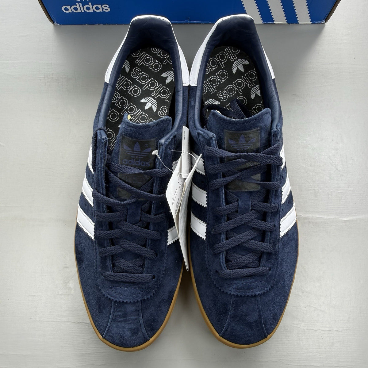 Adidas blue trainers with white and gum sole, featuring gold accents and logo.