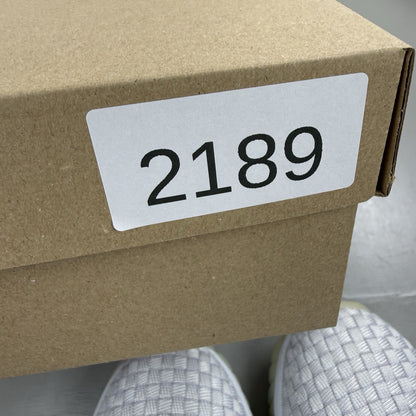 Nike grey trainers with metallic silver accents and minimal orange marks.
