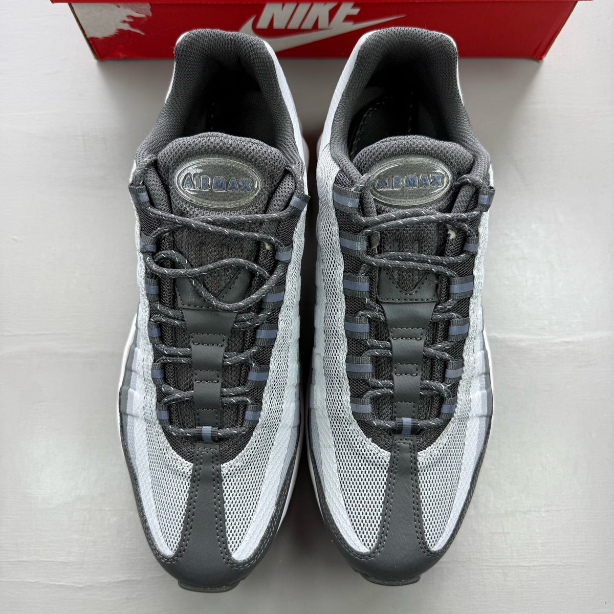 Nike Air Max 95 grey trainers with blue accents and visible logo detailing.