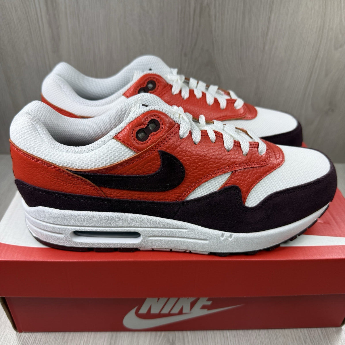 Nike Air Max 1 red trainers with white accents and signature swoosh logo.
