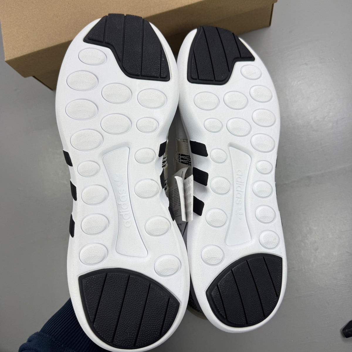 Adidas grey athletic shoes with mesh upper and signature three stripes logo.