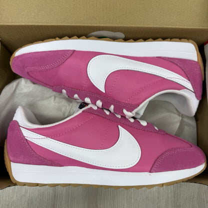 Nike white trainers with pink accents and gum sole, featuring iconic swoosh logo.