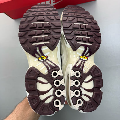 Nike Air Max Plus TN white trainers with burgundy accents and visible logo details.