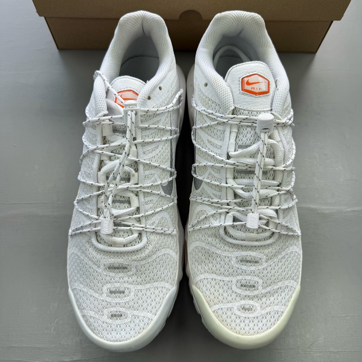 Nike footwear white trainers with orange accents and distinctive Air Max Plus TN design.