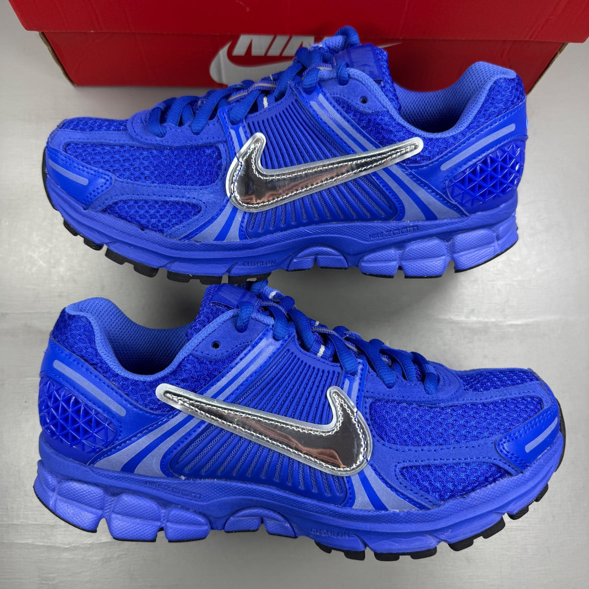 Nike Zoom Vomero 5 blue trainers with silver accents and logo detailing.