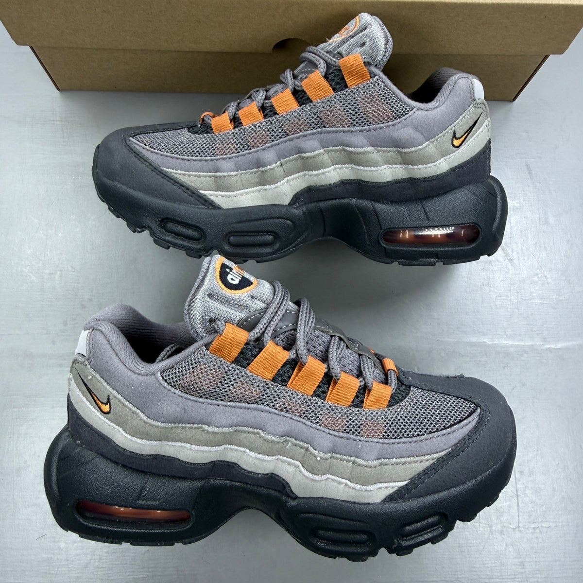 Nike Air Max 95 grey trainers with hot curry and orange accents, mesh and leather material.
