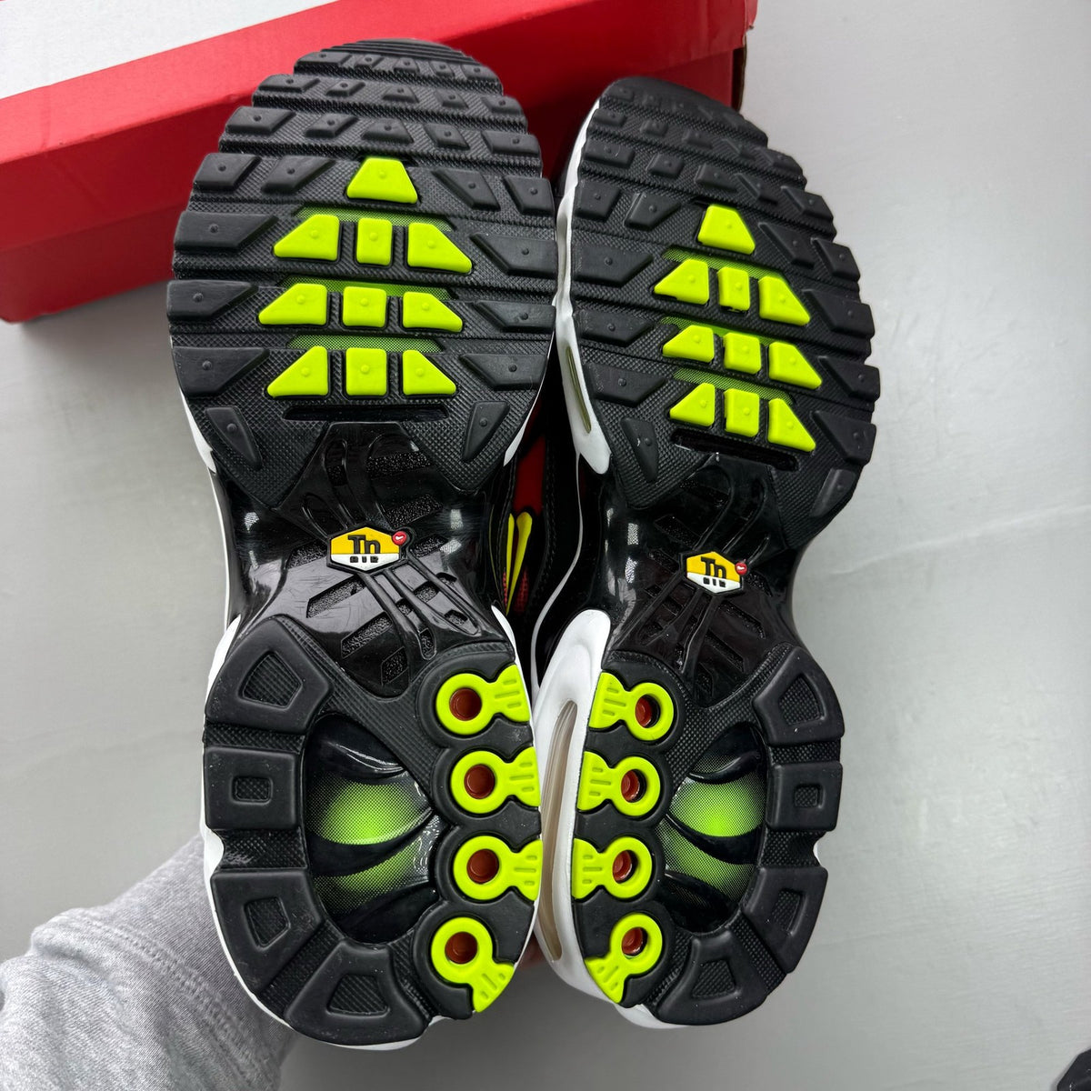 Nike Air Max Plus TN black trainers with light crimson and volt accents, logo on tongue.