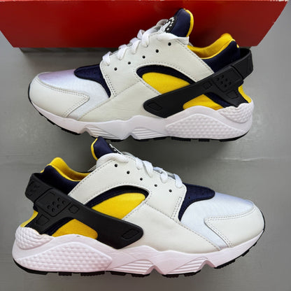 Nike Air Huarache white sneakers with yellow maize and navy accents, featuring logo details.
