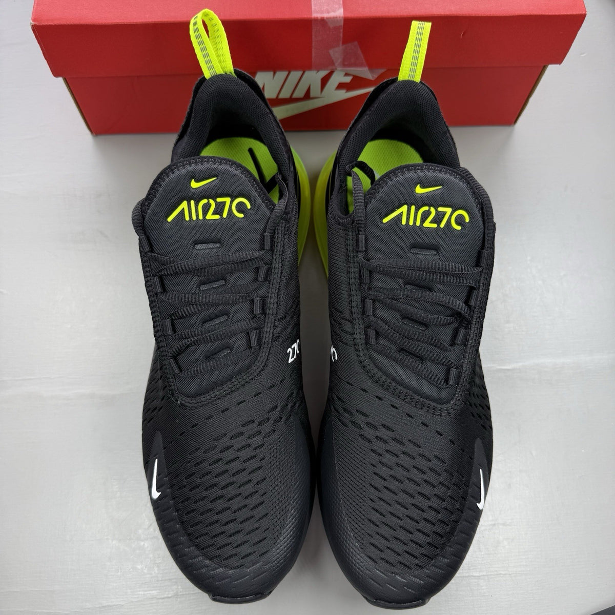 Nike Air Max 270 black trainers with neon volt accents and white sole.