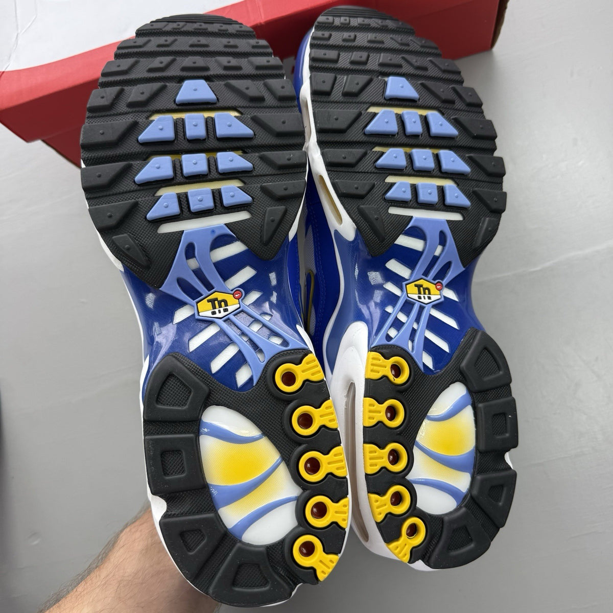 Nike Air Max Plus TN white trainers with blue and yellow accents, mesh upper.