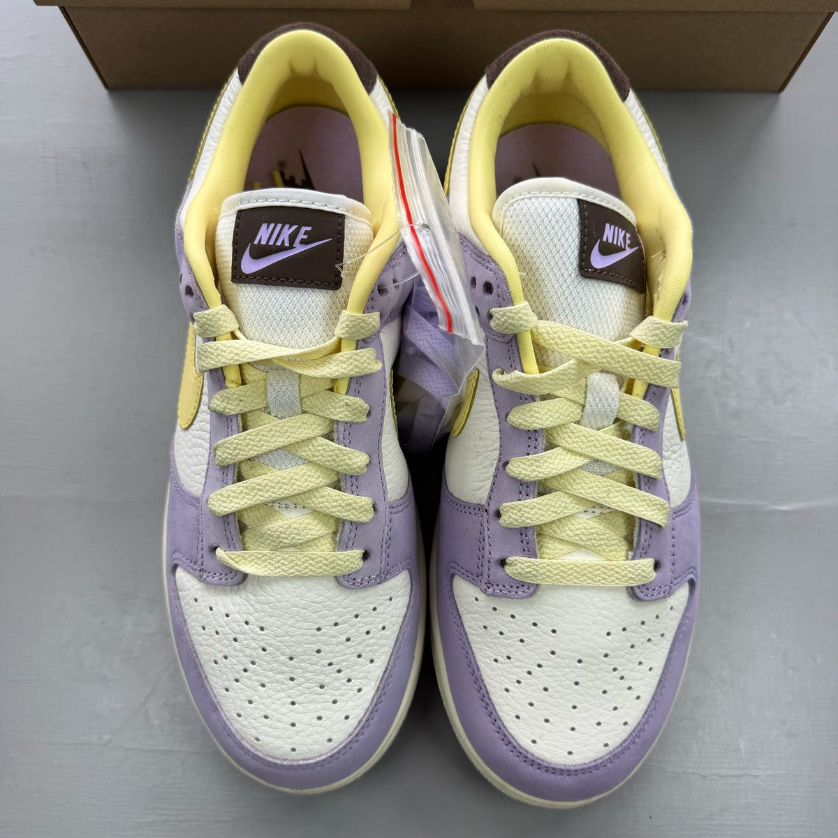 Nike Dunk Low purple trainers with soft yellow accents and classic swoosh logo.