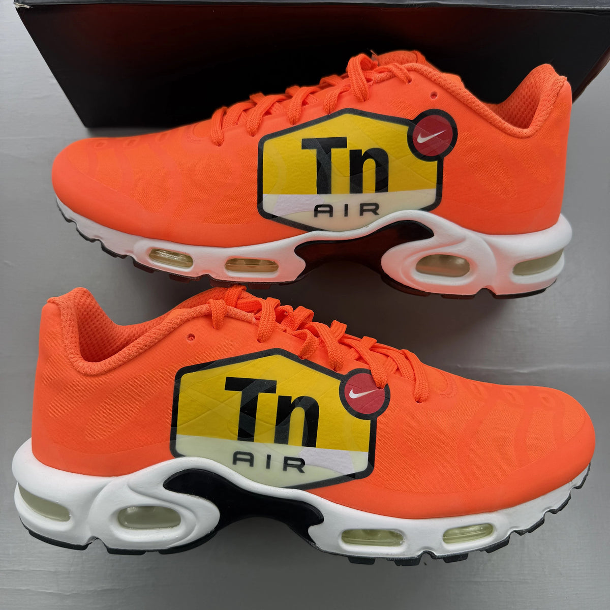 Nike Air Max Plus trainers total orange with large logo and mesh material.