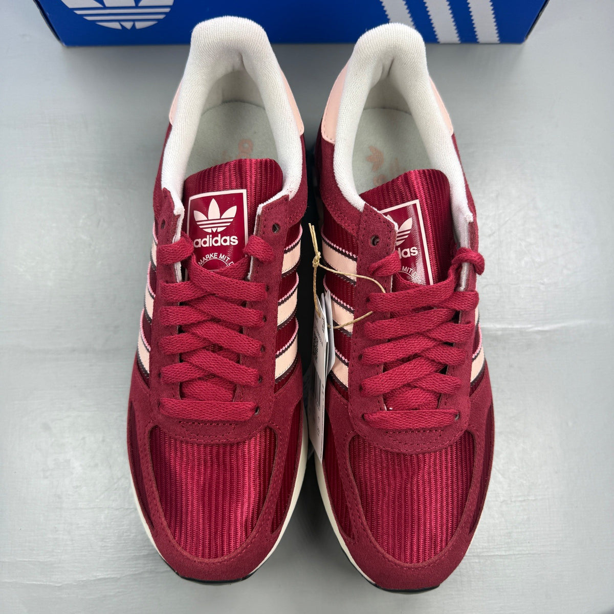 Adidas pink trainers with white stripes and logo, featuring a retro design.