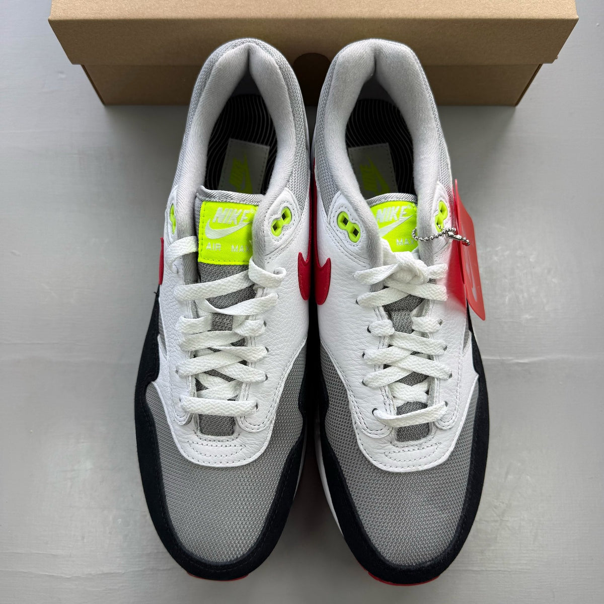 Nike trainers white with chili volt and red accents, featuring iconic swoosh logo.