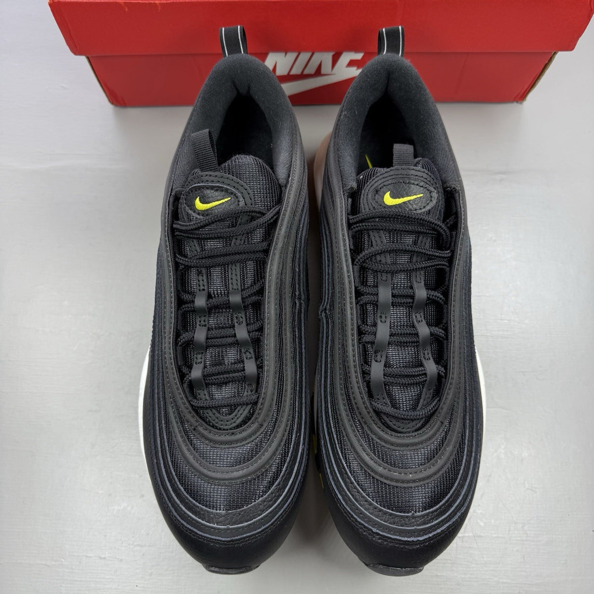 Nike Air Max 97 black trainers with opti yellow accents and white sole.