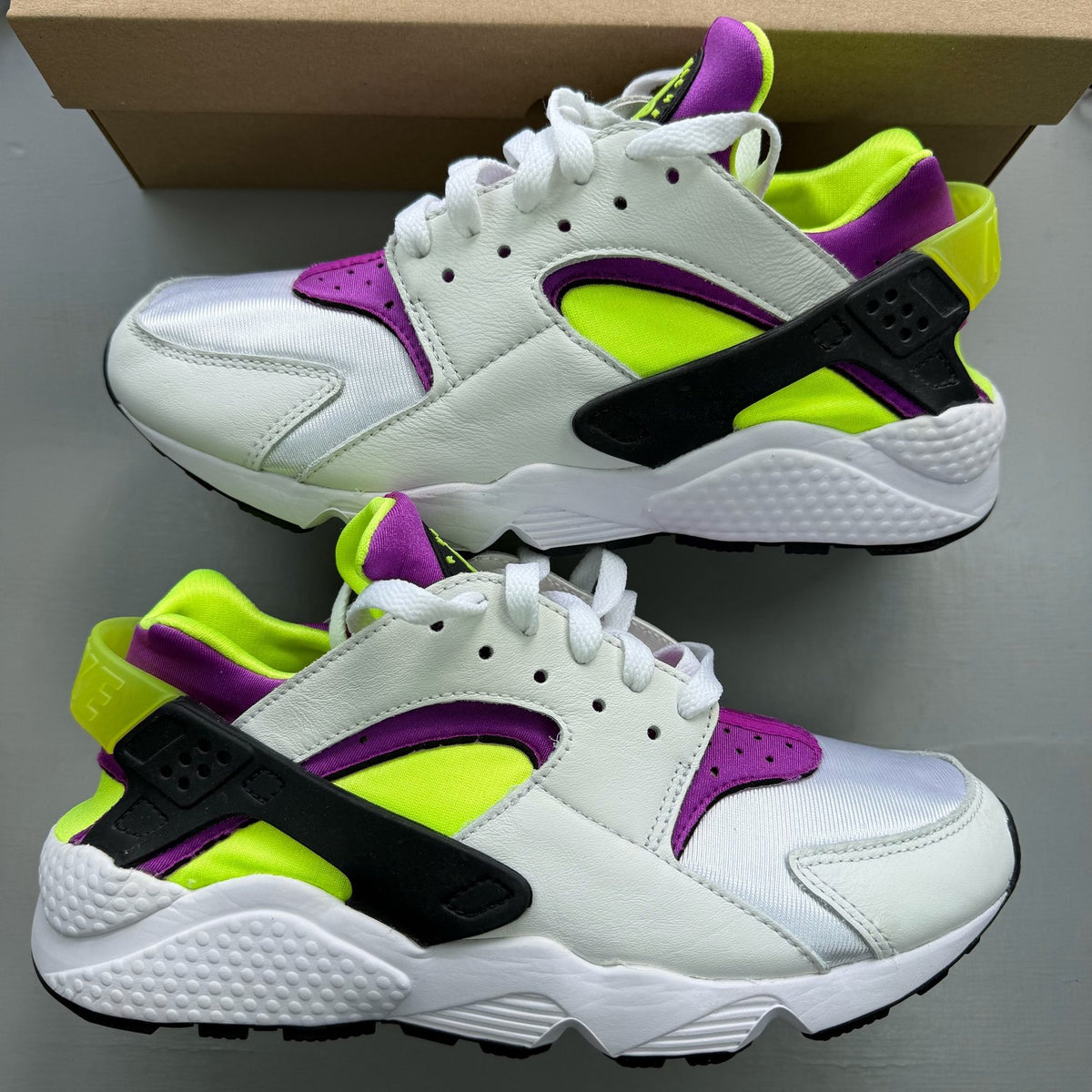 Nike white trainers with magenta and neon yellow accents, featuring classic Huarache design.