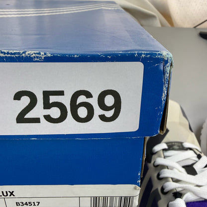Adidas ZX Flux white trainers with purple and black accents, featuring iconic three-stripe logo.