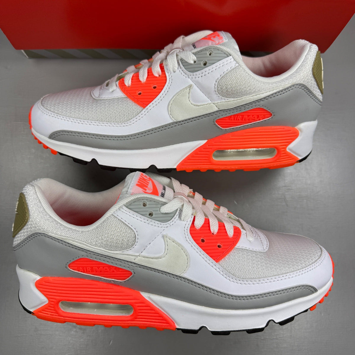 Nike trainers white with hyper orange accents and grey detailing, featuring iconic swoosh logo.