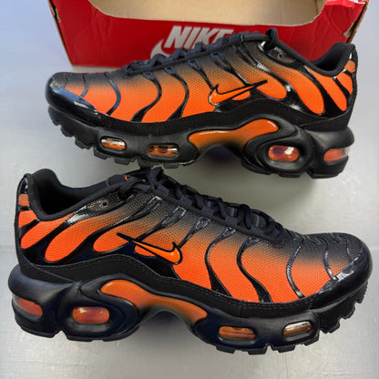 Nike Air Max Plus TN black trainers with orange accents and signature logo details.
