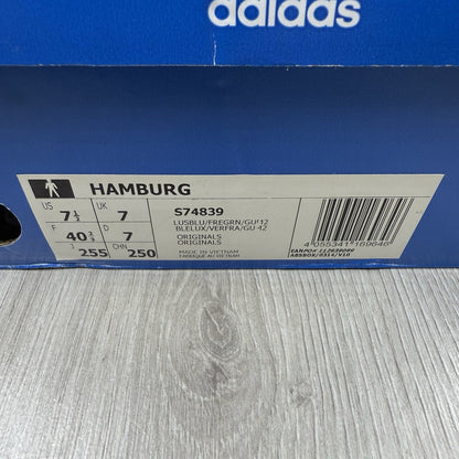 Adidas blue trainers with gum sole and iconic three-stripe logo design.