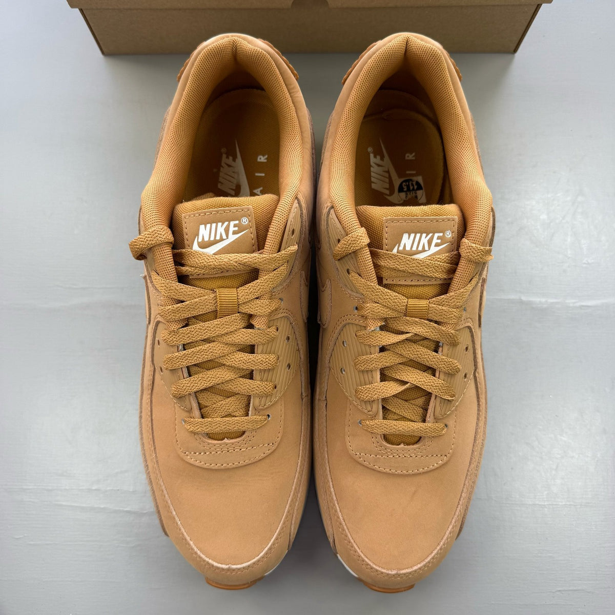 Nike Air Max 90 brown trainers with premium suede material and iconic swoosh logo.