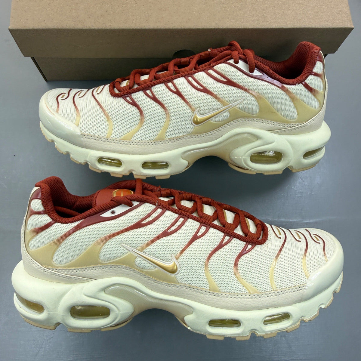 Nike Air Max Plus TN gold trainers with red and white accents, featuring iconic logo.
