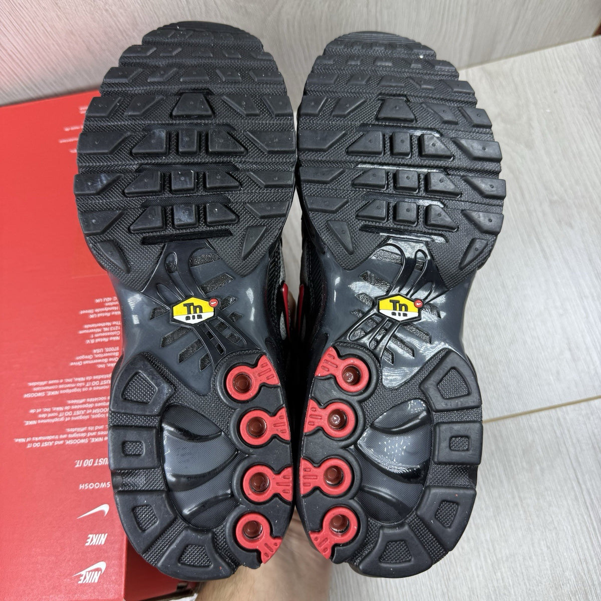 Nike TN Air Max Plus trainers black with red gradient and signature logo design.