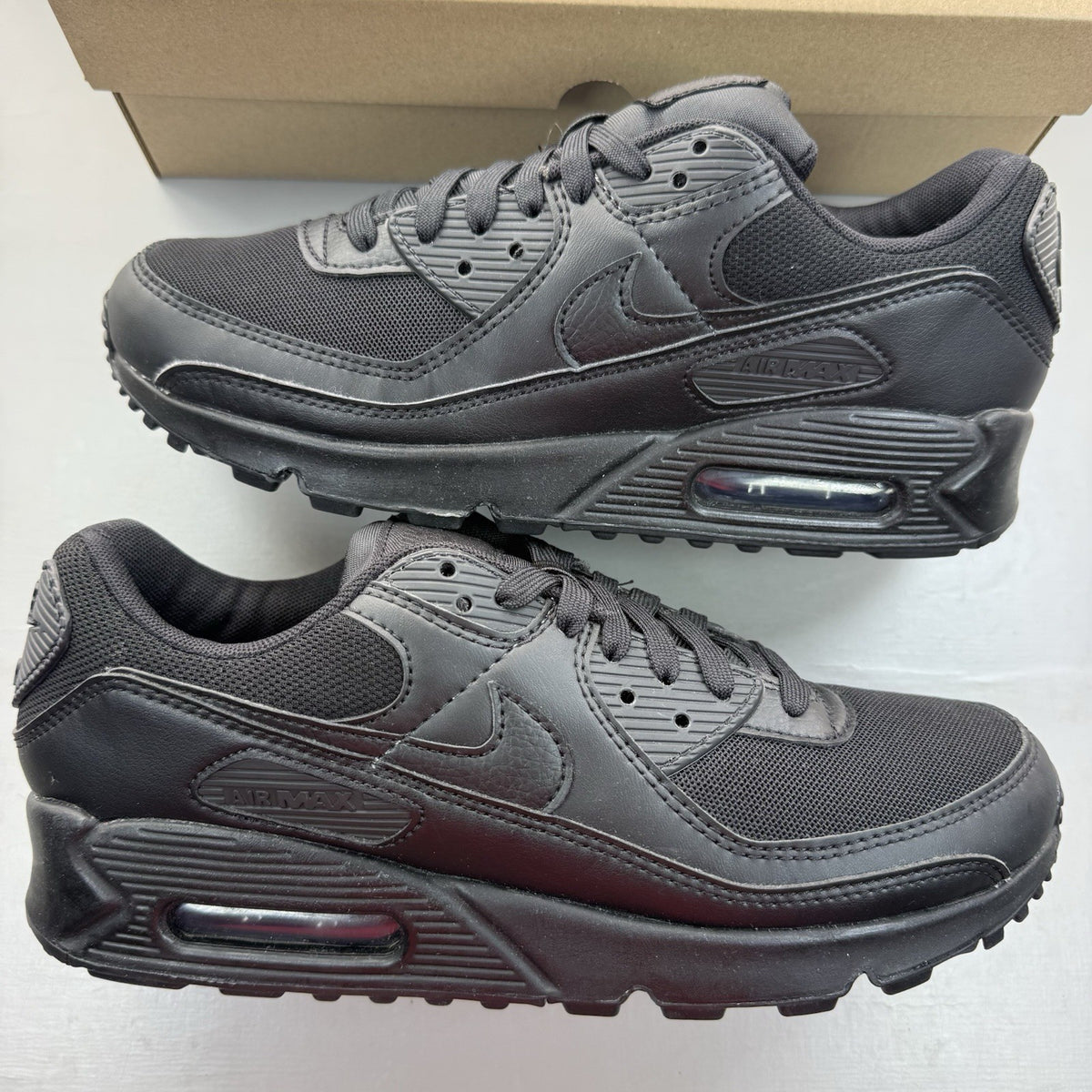 Nike Air Max 90 trainers black with signature logo and textured upper design.
