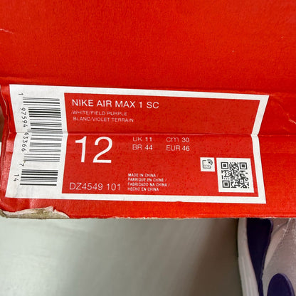 Nike Air Max 1 white trainers with purple accents and logo detail.