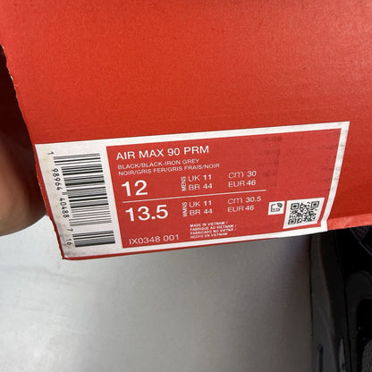 Nike Air Max 90 black trainers with grey accents and iconic logo detail.