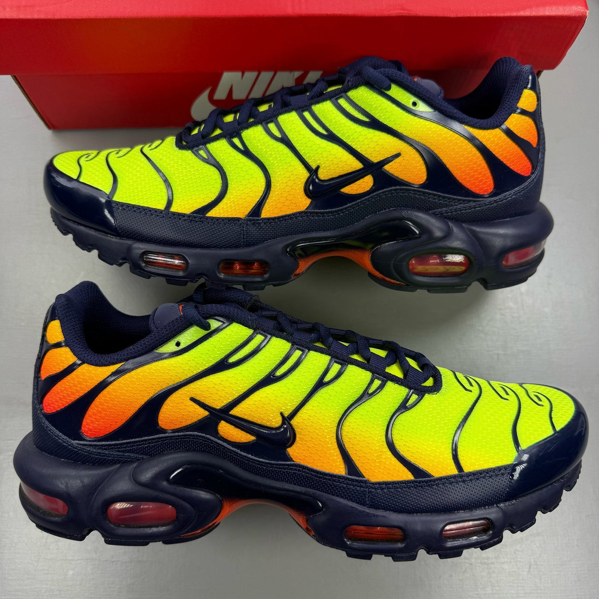Nike yellow trainers with Hyper Crimson accents and distinctive Air Max Plus design.
